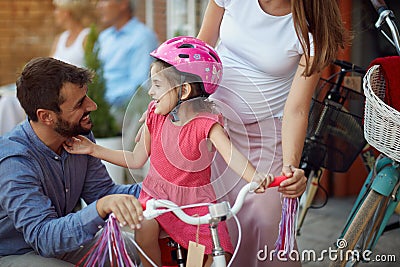 Family buying at happy girl bicycle helmet in bike shop Stock Photo
