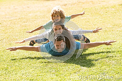Young family with child having fun in nature. Fly concept, little boy is sitting pickaback while imitating the flight. Stock Photo