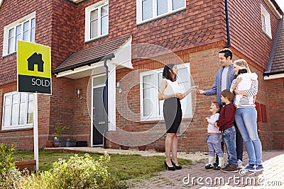 Young Family Collecting Keys To New Home From Realtor Stock Photo