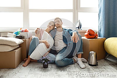 Young family couple bought or rented their first small apartment. Two people sit on floor and look up. They dream. Guy Stock Photo