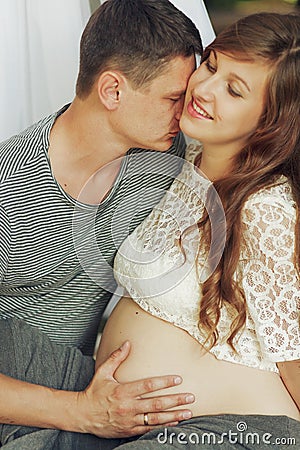 Young family couple portrait, husband and pregnant wife kissing Stock Photo