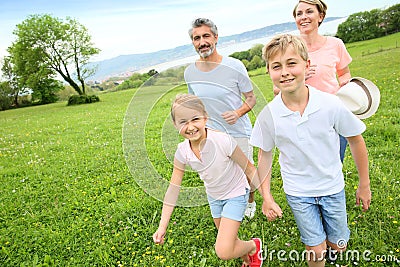 Young family of four running on green grass Stock Photo