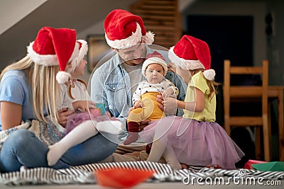Young family gathered for christmas, sitting on the floor at home, enjoying together. baby looking at camera Stock Photo