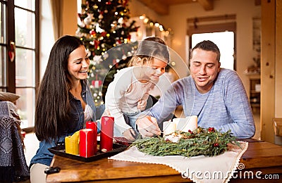 Young family lighting candles on advent wreath. Christmas tree. Stock Photo