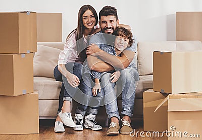 Young Family Moving to New Place and Sits on Sofa. Stock Photo