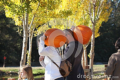 California. USA. October 2012. A young family with pumpkins on their shoulders goes to celebrate Halloween Editorial Stock Photo