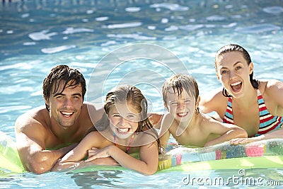 Young Family Relaxing In Swimming Pool Stock Photo