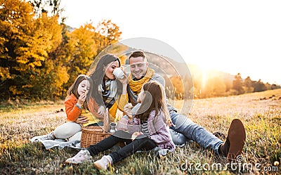 A young family with two small children having picnic in autumn nature at sunset. Stock Photo