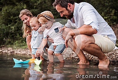 Young family with two toddler children outdoors by the river in summer, playing. Stock Photo