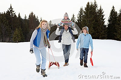 Young Family Walking Through Snow With Sled Stock Photo