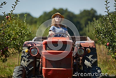 Young farmer woman driving her old tractor Stock Photo