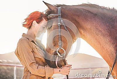 Young farmer woman hugging her horse - Cowgirl having fun inside equestrian corral ranch - Concept about love between people and Stock Photo