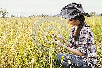 Young farmer woman sitting and looking at rice happily Successful business woman farmer planting rice. Stock Photo