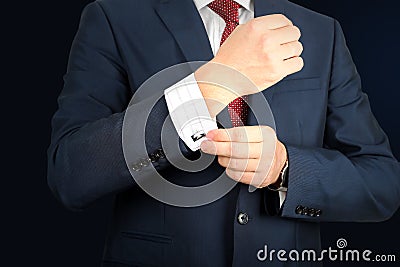 Young fashion buisness man in a blue/navy suit touching at his cufflinks Stock Photo