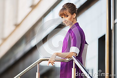 Young fashion business woman wearing purple blazer walking in city street Stock Photo