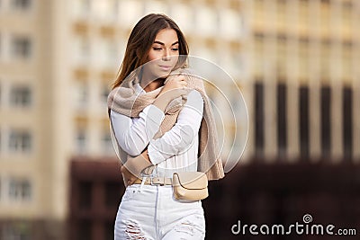 Young fashion woman in white shirt and ripped jeans walking in street Stock Photo