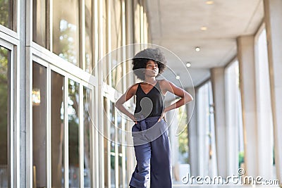 A young fashionable Afro-American woman walking down the street with her hands on her waist Stock Photo