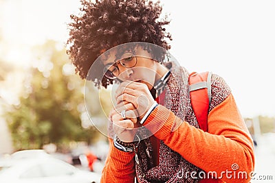 Young fashionable dressed curly black African American A student with a backpack standing against the background of glass walls Stock Photo