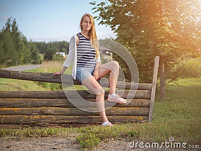 Young fashionable happy blonde woman posing in rural landscape. Stock Photo