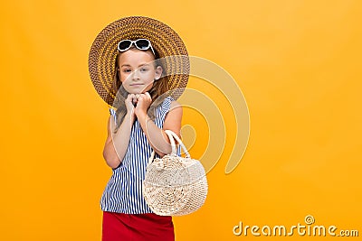 Young fashionista girl flirts in a straw hat on a yellow background with copy space Stock Photo