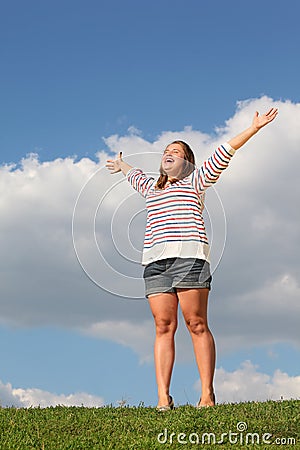 Young fat girl stands at grass, raises her hands Stock Photo