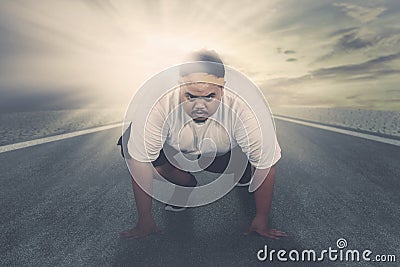 Young fat man ready to run on the road Stock Photo