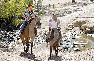 Young father as horse instructor of young teen daughter riding little pony wearing cowgirl hat Stock Photo