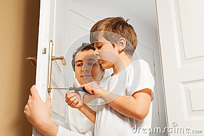 Young father helping his son to fix door-handle Stock Photo