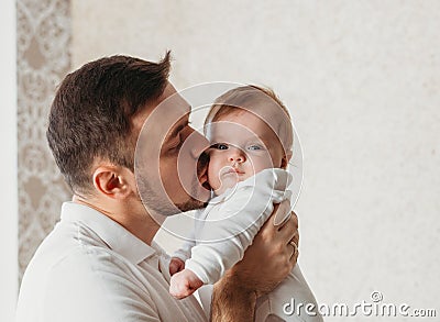 Young father kisses baby daughter in a light room close-up Stock Photo