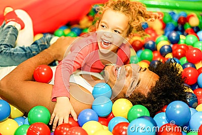 Young father playing with his daughter inside ball pit swimming pool - Happy people having fun in children playground indoor - Stock Photo