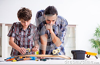 Young father repairing skateboard with his son at home Stock Photo