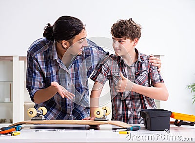 Young father repairing skateboard with his son at home Stock Photo
