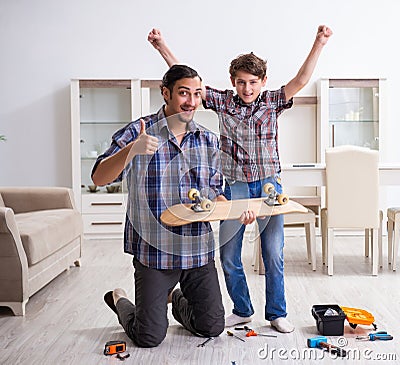 Young father repairing skateboard with his son at home Stock Photo