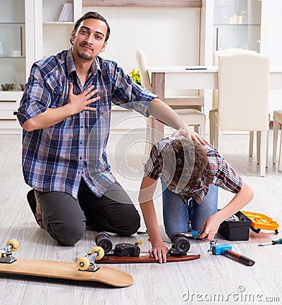 Young father repairing skateboard with his son at home Stock Photo