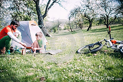 Young father showing his son how to make campfire during during a bicycle trip Stock Photo