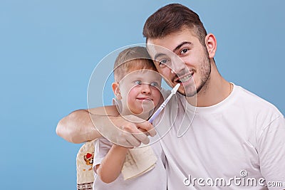 A father with a small son, having fun together, father is teaching his son to brush teeth with a toothbrush. Stock Photo