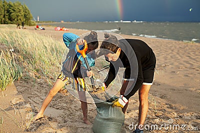 Young father with son on beach digging pit under the rainbow, playing, looking for treasure, lifestyle happy family on Stock Photo