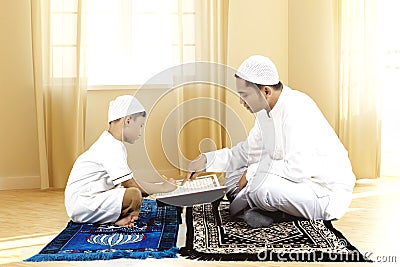 Young father teaching Quran to his son Stock Photo