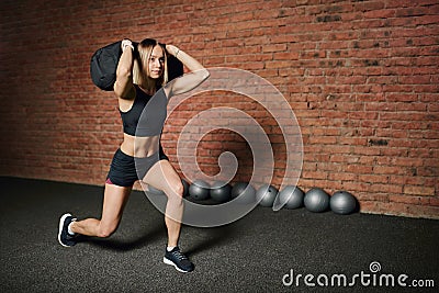 Caucasian athletic woman working out with sandbag while exercises in the gym. Stock Photo