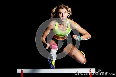 Young female athlete jumping over hurdle in sprint Stock Photo