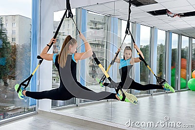 Young female athletic doing exercises training legs with trx straps in fitness gym Stock Photo