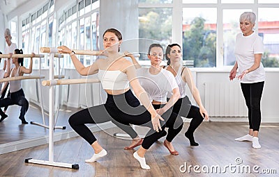 Young female ballet dancer practicing grand plie at barre Stock Photo