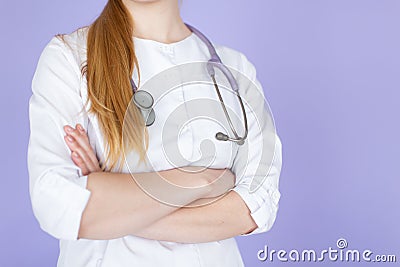 Young female blonde doctor with crossed hands with stethoscope on her neck on purple background Stock Photo