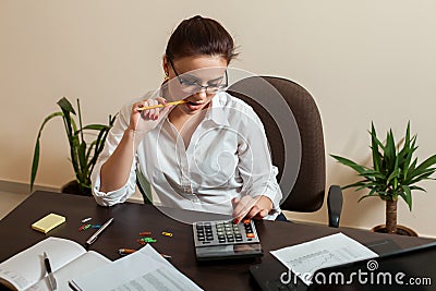 Young female bookkeeper considers on calculator Stock Photo