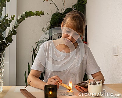 Young female burning aromatic sandalwood stick. Aromatherapy incense. Meditation and relaxation Stock Photo