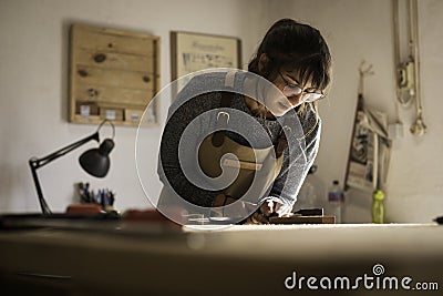 A young female carpenter working as wood designer in a small carpentry workshop. Young business woman handcrafting a piece of Stock Photo