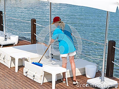 Young female cleaning summer beach loungers. Person working using tools Editorial Stock Photo