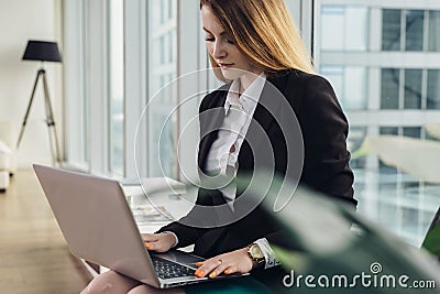 Young female copywriter writing an advertising text typing on laptop keyboard sitting in office Stock Photo