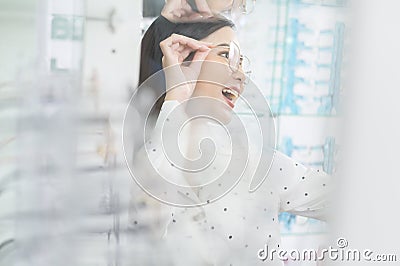 Young female customer trying on glasses and taking a selfie in optical center, Eyecare concept Stock Photo