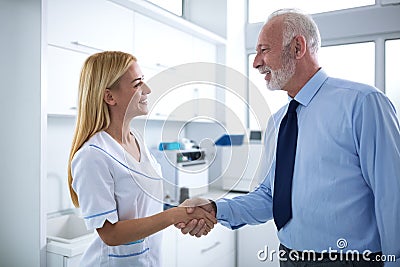 Young female dentist and patient are shaking hands Stock Photo